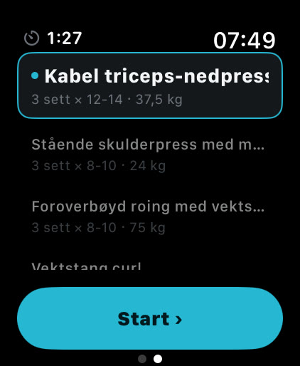 Øvelseslisten i Musklr på Apple Watch mellom to øvelser: Kabel triceps-nedpress med V-stangfeste valgt, 3 sett med 12 til 14 reps på 37,5 kg, og en Start-knapp